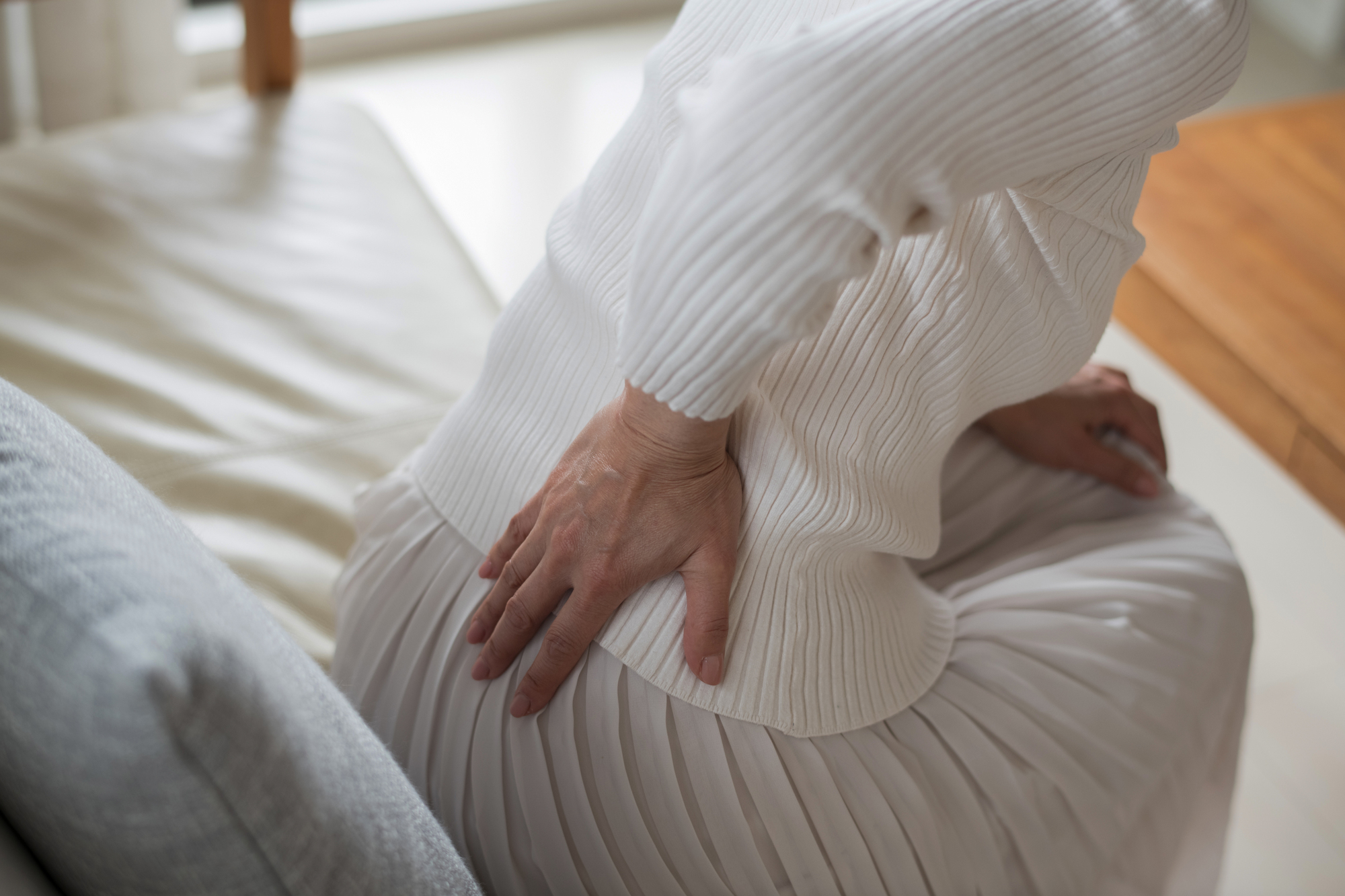 背中の痛みを感じる女性│整形外科で対応可能な症状イメージ